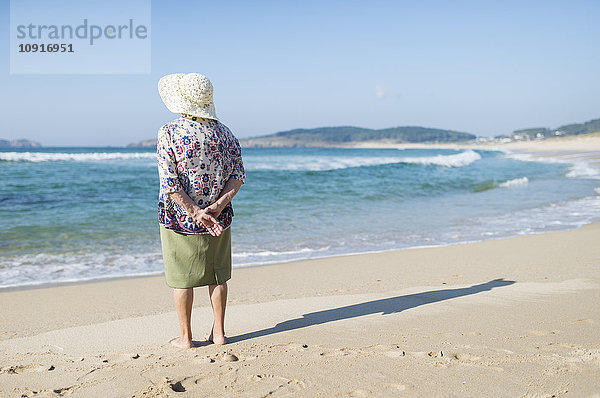 Rückansicht der Seniorin am Strand stehend