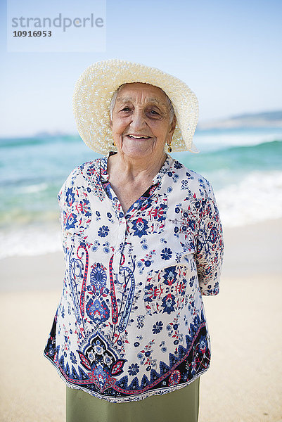 Porträt einer lächelnden Seniorin am Strand stehend