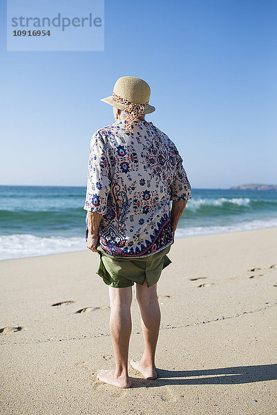 Rückansicht der Seniorin am Strand stehend