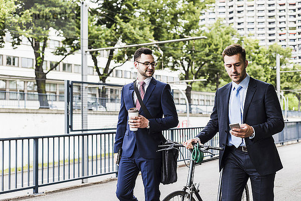 Geschäftsleute  die mit dem Fahrrad in der Stadt spazieren gehen und sich unterhalten.