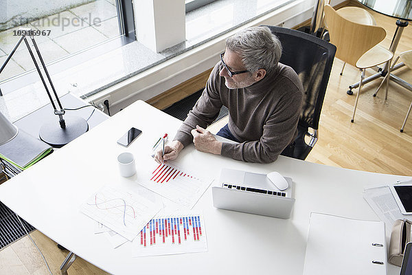 Älterer Mann im Büro mit Diagrammen