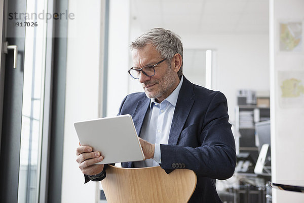 Erfolgreicher Geschäftsmann in seinem Büro mit digitalem Tablett