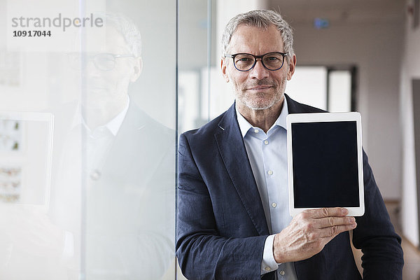 Erfolgreicher Geschäftsmann mit digitalem Tablett im Büro