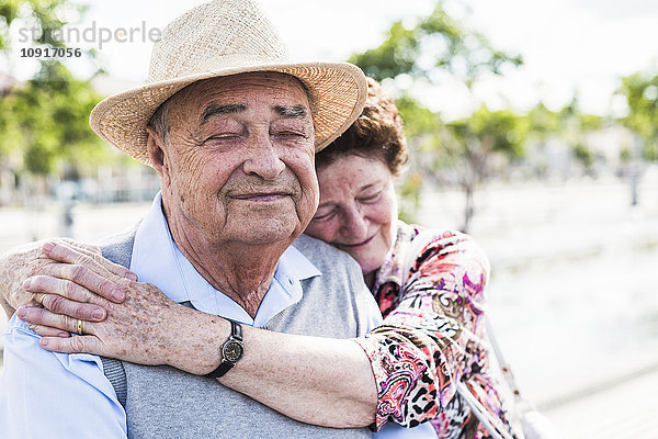 Porträt eines älteren Mannes mit geschlossenen Augen  der Intimität mit seiner Frau genießt.