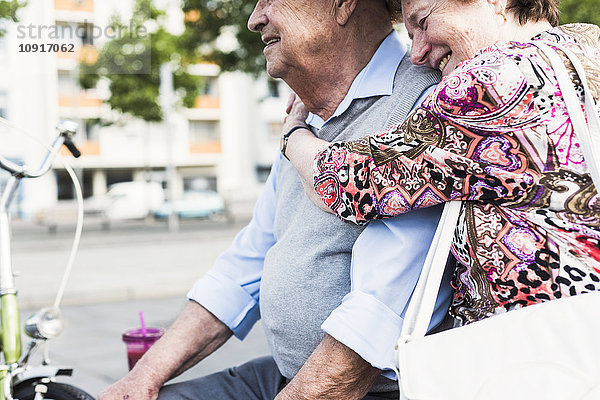 Seniorin mit Kopf auf der Schulter ihres Mannes auf einer Bank sitzend