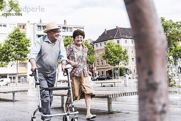 Älterer Mann  der mit seiner Frau auf Rädern spazieren geht.