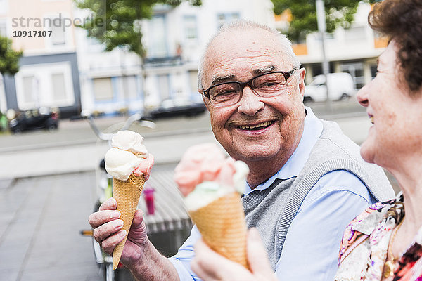 Porträt eines glücklichen älteren Mannes mit Eistüte  der seine Frau ansieht.
