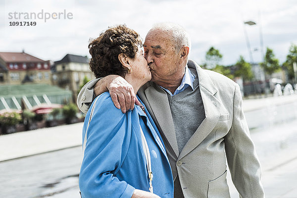 Ein älterer Mann  der seine Frau küsst.