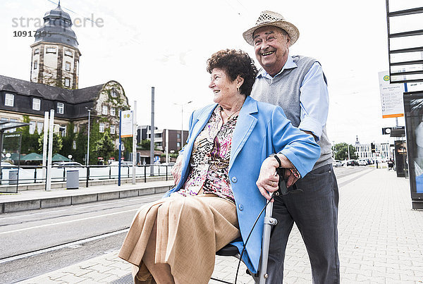 Deutschland  Mannheim  glückliches Seniorenpaar mit Rollator wartet am Bahnhof