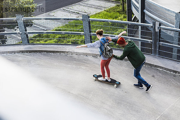 Junges Paar mit Skateboard im Parkhaus