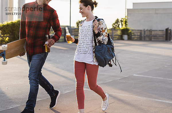 Junges Paar mit Bierflaschen und Skateboard im Freien