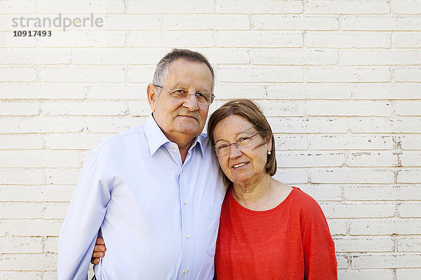 Porträt eines älteren Ehepaares vor weißer Backsteinmauer