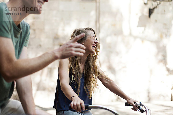 Lachende Frau mit Fahrrädern neben ihrem Partner