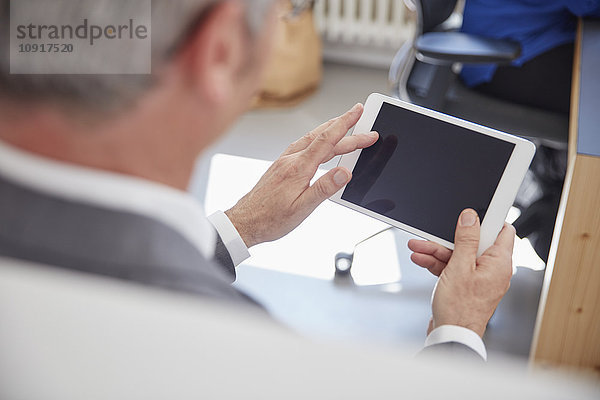 Erwachsener Mann mit digitalem Tablett im Büro