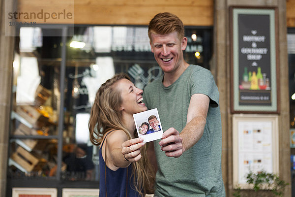 Glückliches Paar  das sich selbst vor einem Coffee-Shop zeigt.