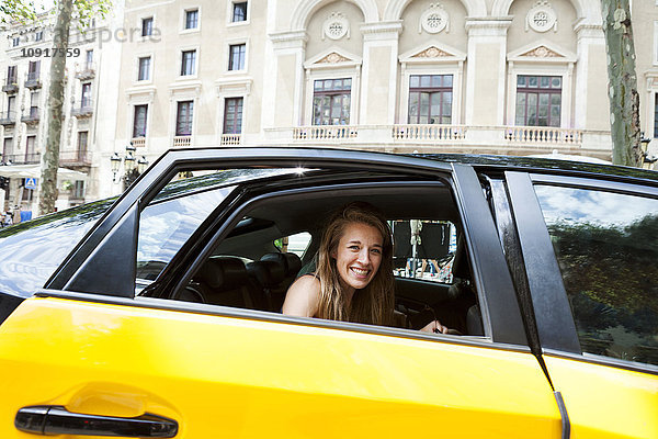 Spanien  Barcelona  glückliche junge Frau mit Blick aus dem Taxi-Fenster