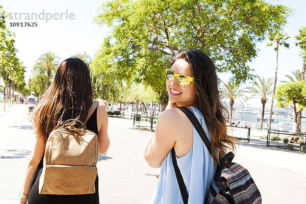 Spanien  Barcelona  Porträt einer lächelnden Frau mit Sonnenbrille beim Spaziergang mit ihrer besten Freundin