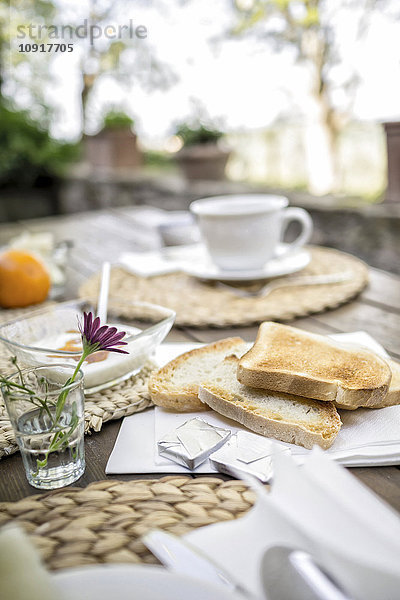Brot  Blume  Joghurt und Tasse Kaffee auf Gartentisch