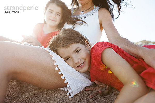 Porträt eines kleinen Mädchens zusammen mit Mutter und Schwester am Strand