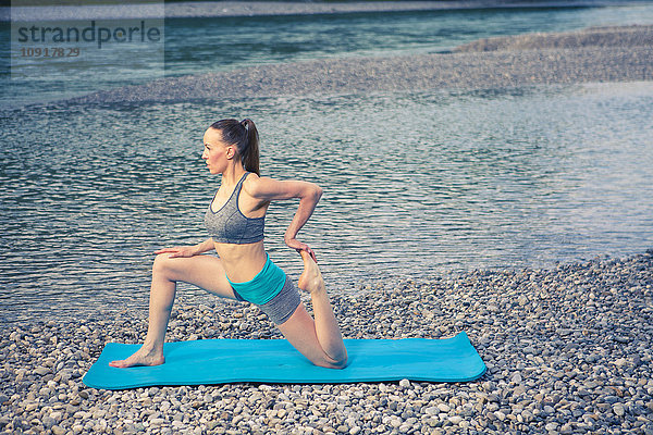 Frau beim Yoga am Flussufer