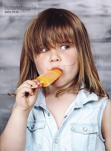 Porträt eines kleinen Mädchens  das Eis am Stiel isst.