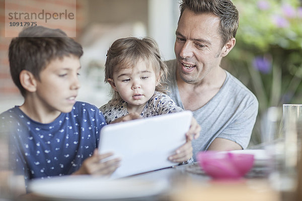 Vater und seine Kinder beim gemeinsamen Betrachten des digitalen Tabletts