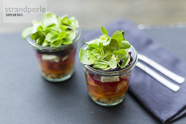 Regenbogensalat im Glas mit Kichererbsen  Tomaten  Karotten  Rotkohl  Radieschen  Salat und Fetakäse