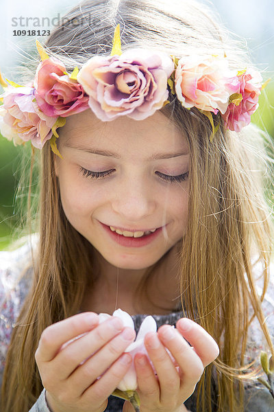 Porträt eines lächelnden Mädchens mit Blumenkranz mit Magnolienblüte in den Händen