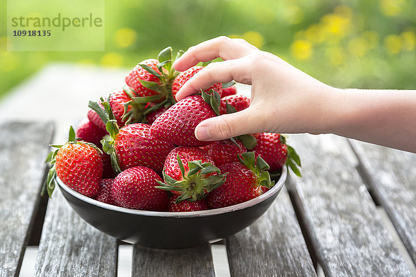 Mädchenhand nimmt Erdbeere