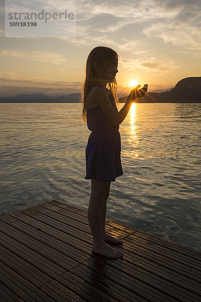 Mädchen hält bei Sonnenuntergang Händchen gegen die Sonne