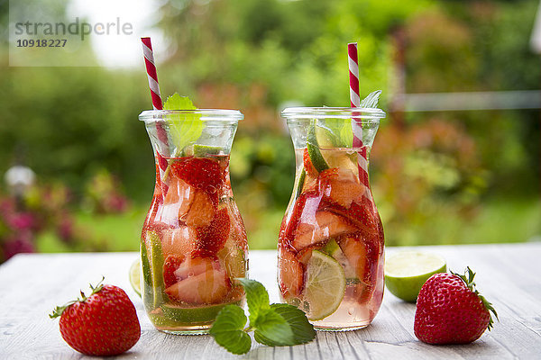 Zwei Glasflaschen Entgiftungswasser mit Erdbeeren und Limette