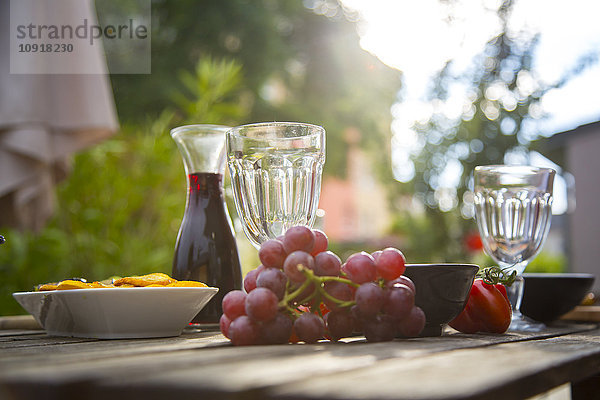 Mediterrane Antipasti und Wein auf dem Gartentisch
