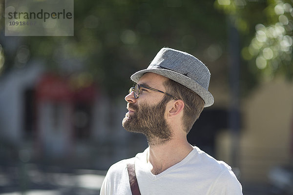 Bärtiger Mann im Freien mit Hut und Brille
