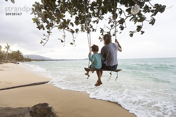 Thailand  Familie am Strand  sitzend auf Schaukel