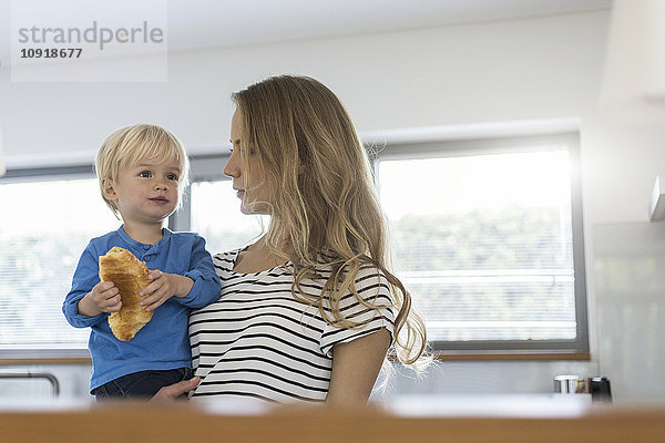 Mutter hält Sohn beim Croissant essen