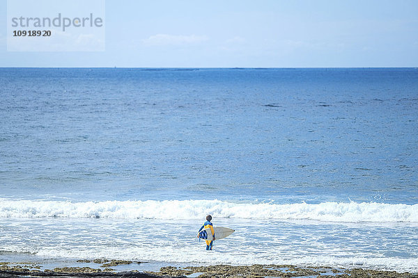 Spanien  Teneriffa  Junge mit Surfbrett im Meer