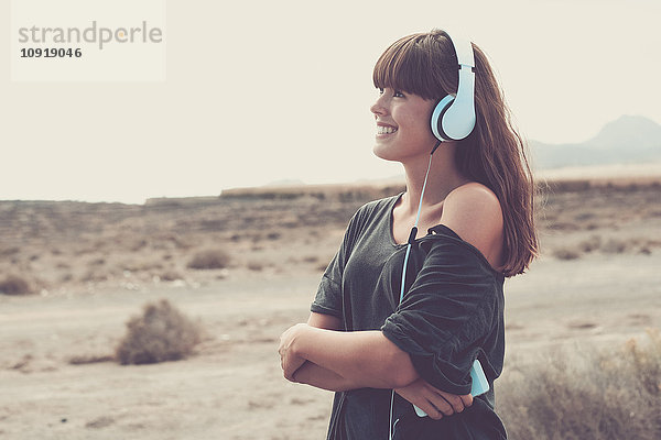Junge Frau hört Musik und lächelt fröhlich.