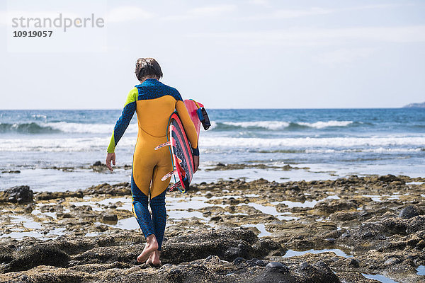 Spanien  Teneriffa  junger Surfer mit Surfbrett