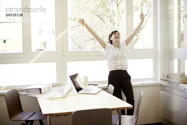 Lachende Frau beim Stretching in ihrem Büro
