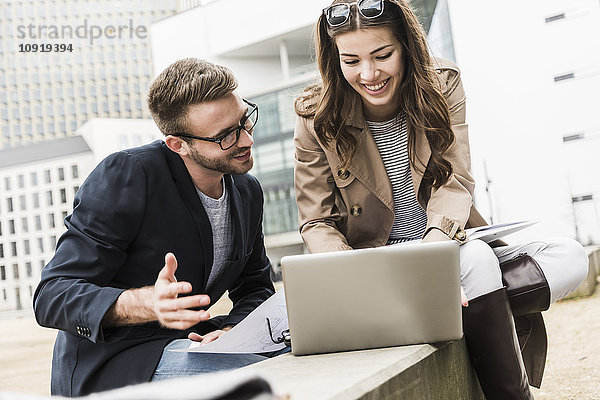 Junges Geschäftspaar bei der Zusammenarbeit im Freien mit dem Laptop