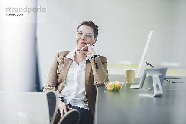 Senior Managerin sitzt im Büro  die Füße hoch.