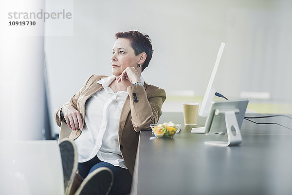 Senior Managerin im Büro sitzend  Blick zur Seite