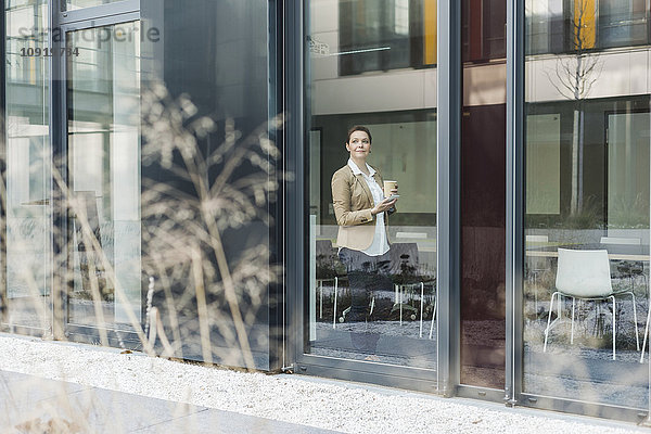 Senior Managerin auf der Fensterscheibe stehend  Kaffeetasse