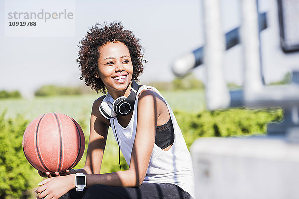 Lächelnde junge Frau hält Basketball