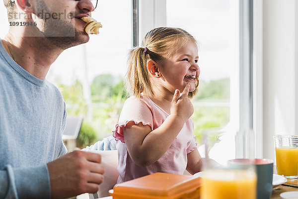 Verspielter Vater und Tochter mit Essen im Mund