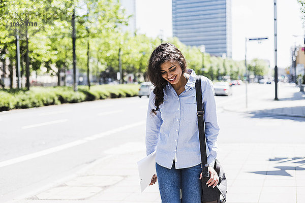 Lächelnde junge Frau unterwegs in der Stadt