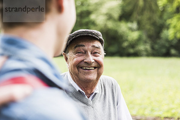 Porträt eines älteren Mannes im Gespräch mit seinem Enkel