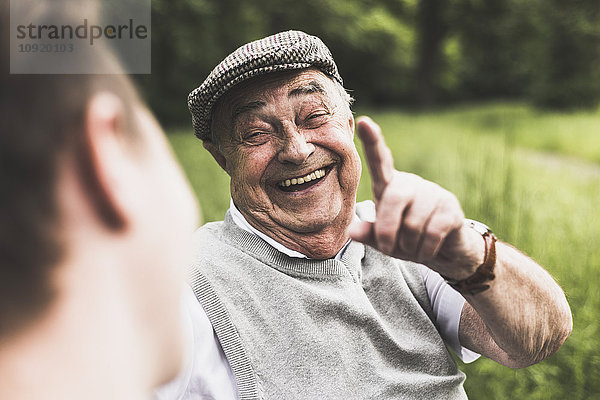 Porträt eines lachenden älteren Mannes im Gespräch mit seinem Enkel