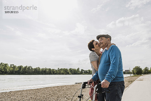 Älterer Mann und seine Tochter stehen am Flussufer.