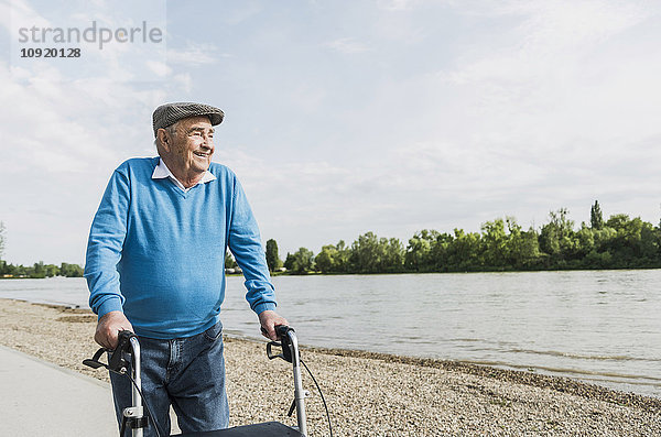 Lächelnder älterer Mann beim Spaziergang mit Radwanderer am Flussufer